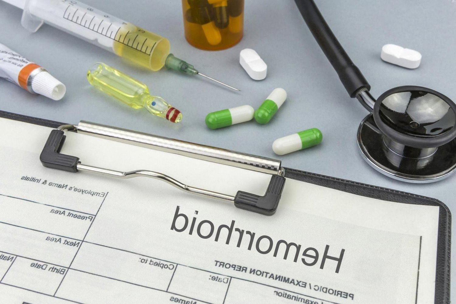 Hemorrhoid examination report with medication, syringe and stethoscope on a clinical desk