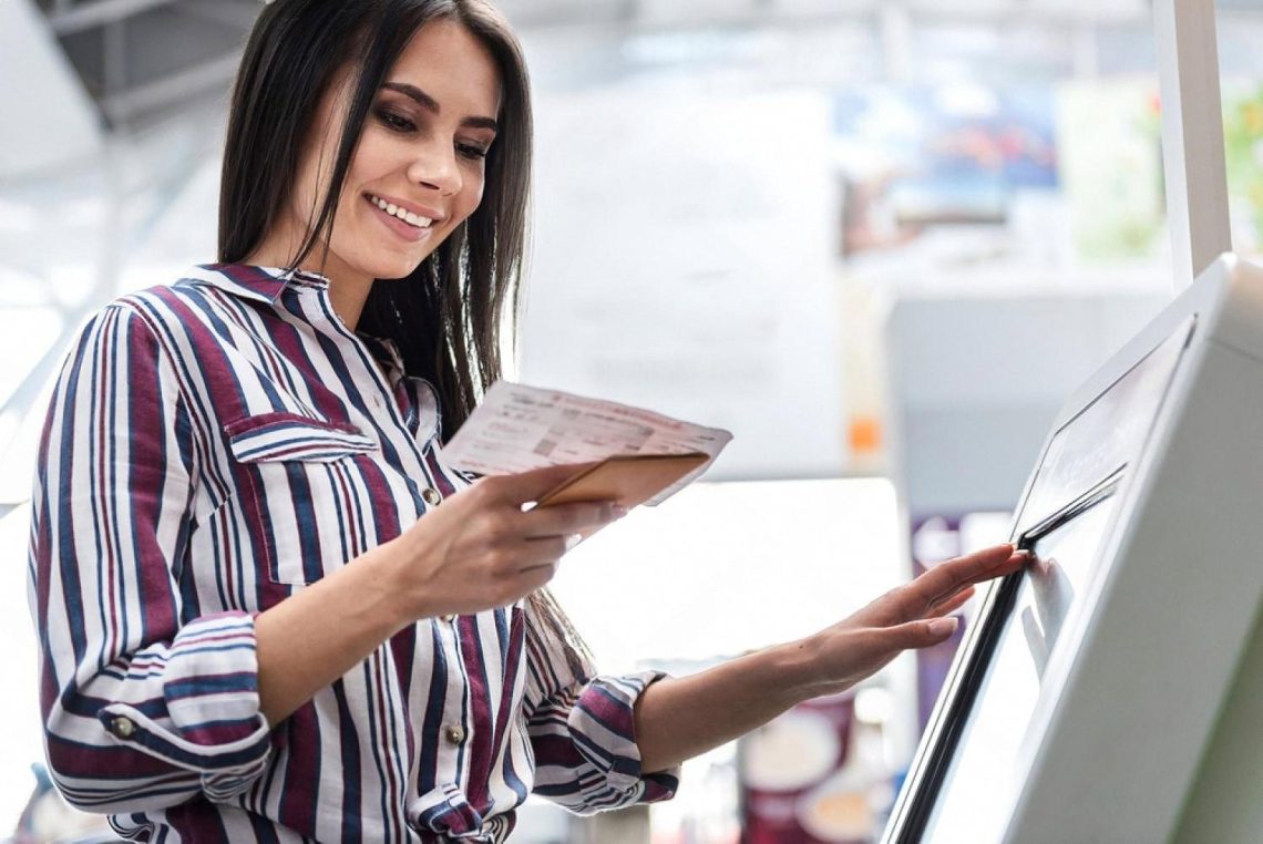 Woman using a self-service kiosk to check in with her booking code