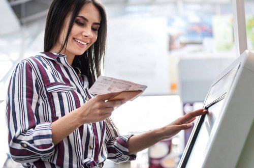 Woman using a self-service kiosk to check in with her booking code